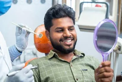 man looking at his new dental implants in the mirror